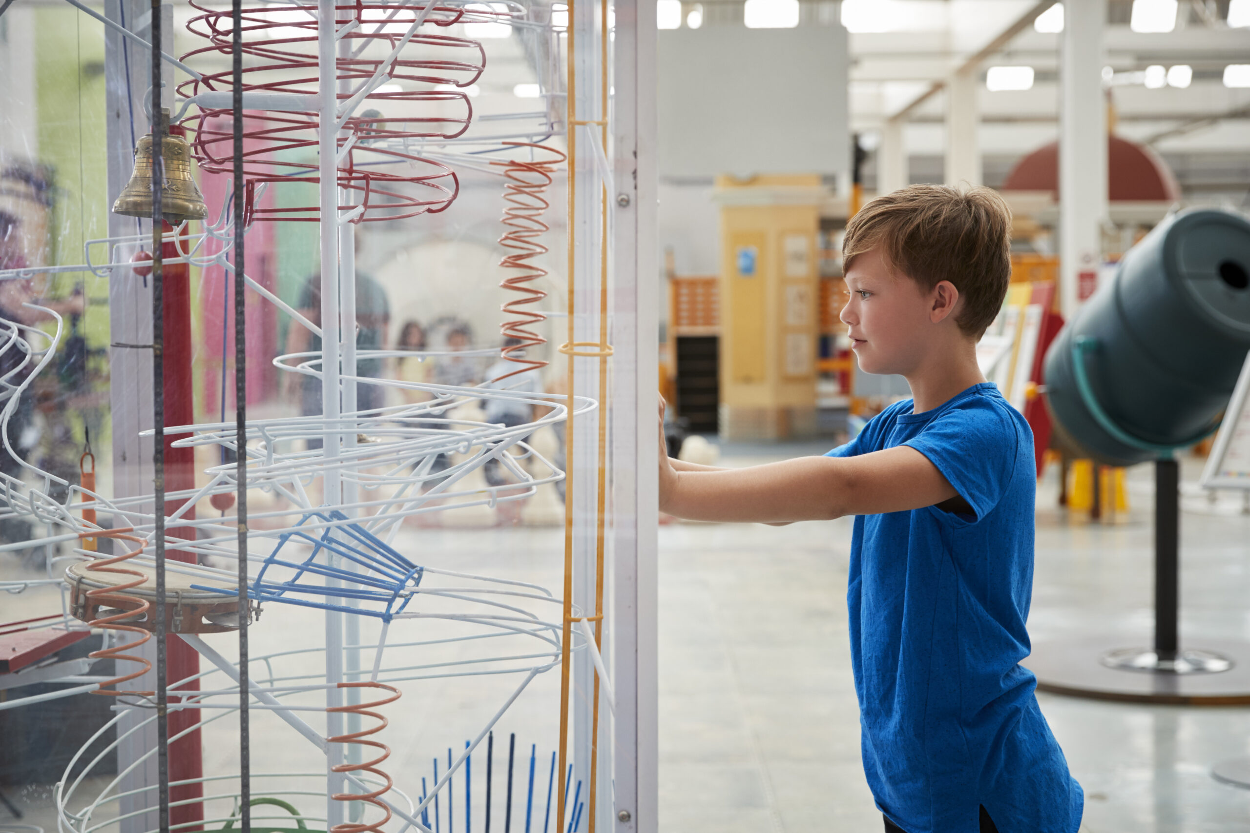 Boy in blue shirt explores marble run exhibit at science museum.