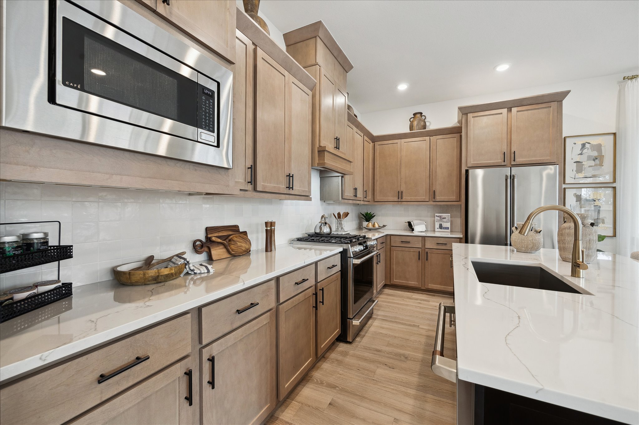 Modern kitchen with light wood cabinets, white countertops, and stainless steel appliances.