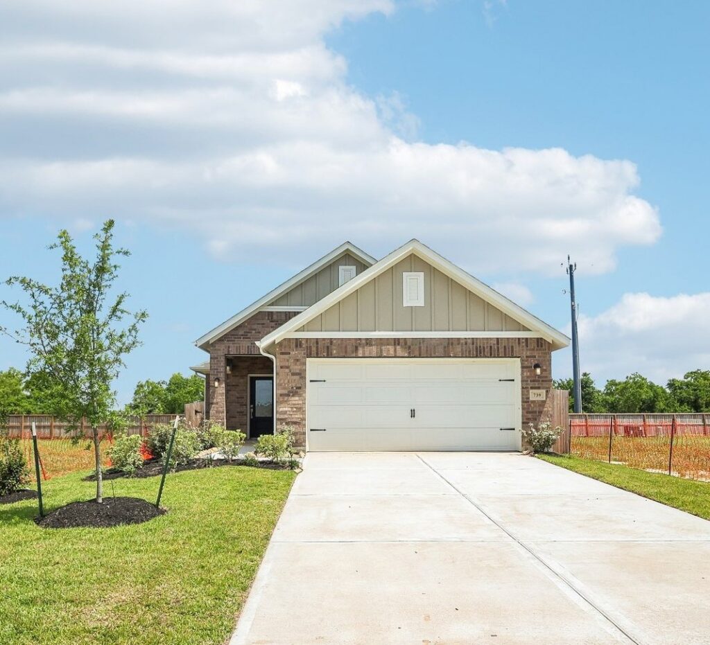 Single-story suburban house with brick facade, attached garage, and a landscaped front yard.