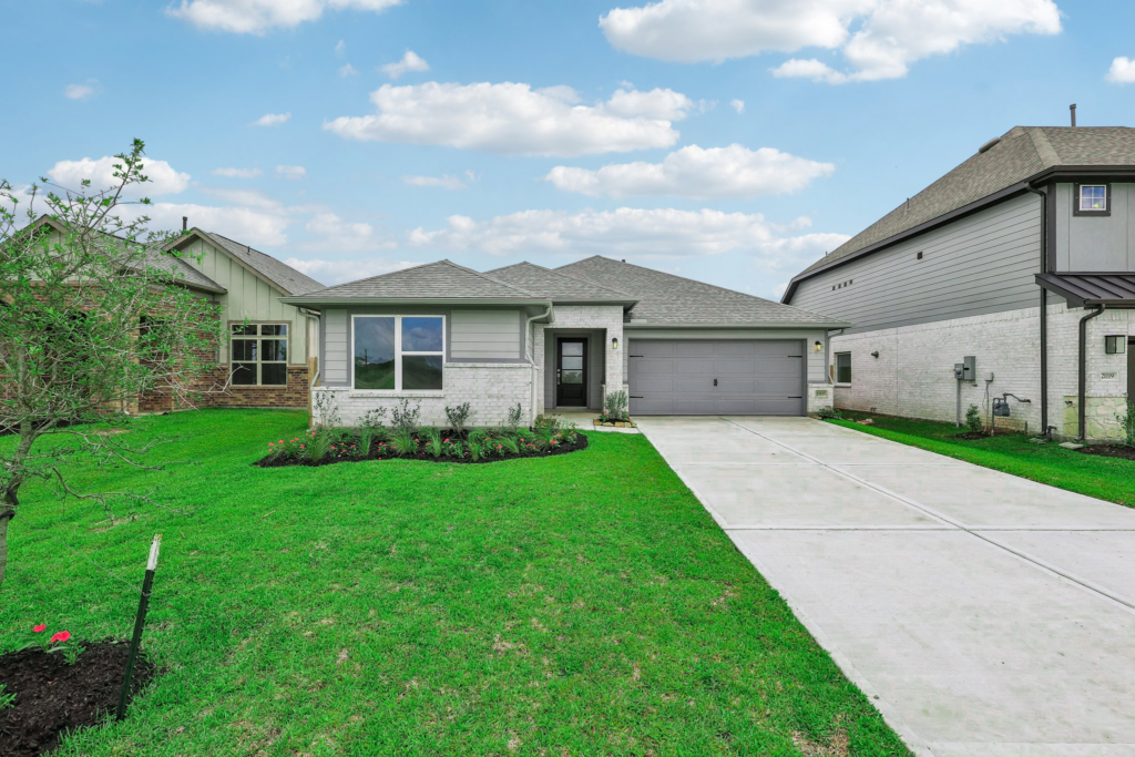 Single-story suburban house with gray siding, two-car garage, and well-kept front lawn.