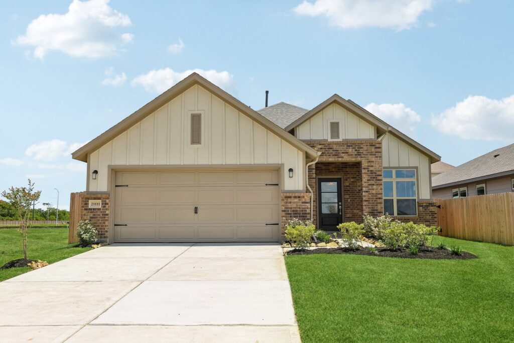 Single-story house with a two-car garage, brick and siding exterior, and manicured lawn.