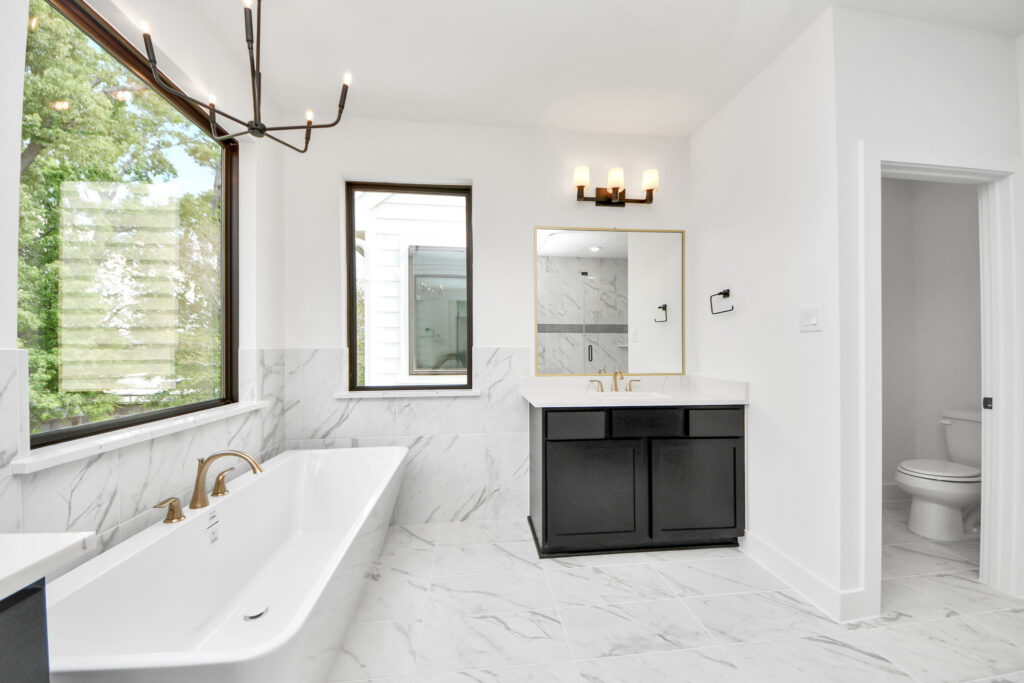 Modern white bathroom with marble tile, a soaking tub, and a dark vanity.